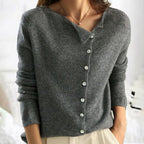Femme portant un pull beige asymétrique avec boutons, manches longues, col bateau. Mode élégante, tendance automne-hiver, style décontracté chic.