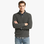 Homme portant un pull en laine bordeaux avec fermeture éclair, chemise à carreaux bleue et jean décontracté. Mode automne-hiver élégante et confortable.